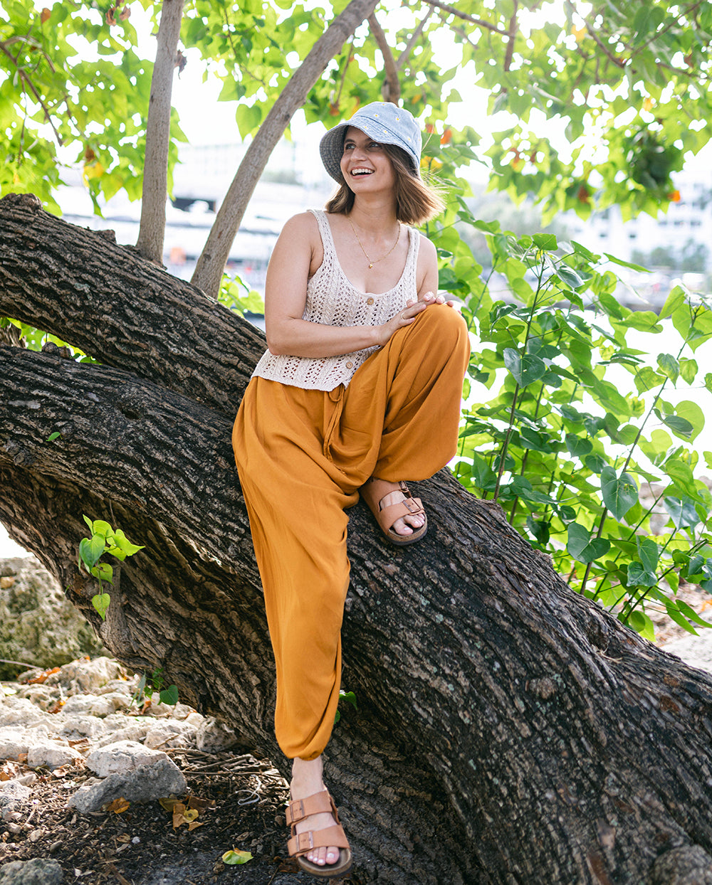 Woman sitting on a tree branch surrounded by greenery. #color_amber