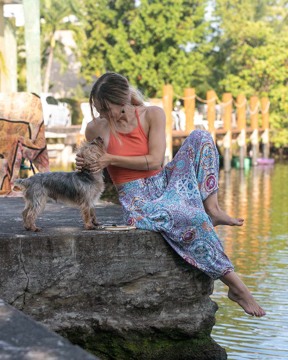 woman in purple galactic harem pants sitting with dog near a stream #color_purple Galactic