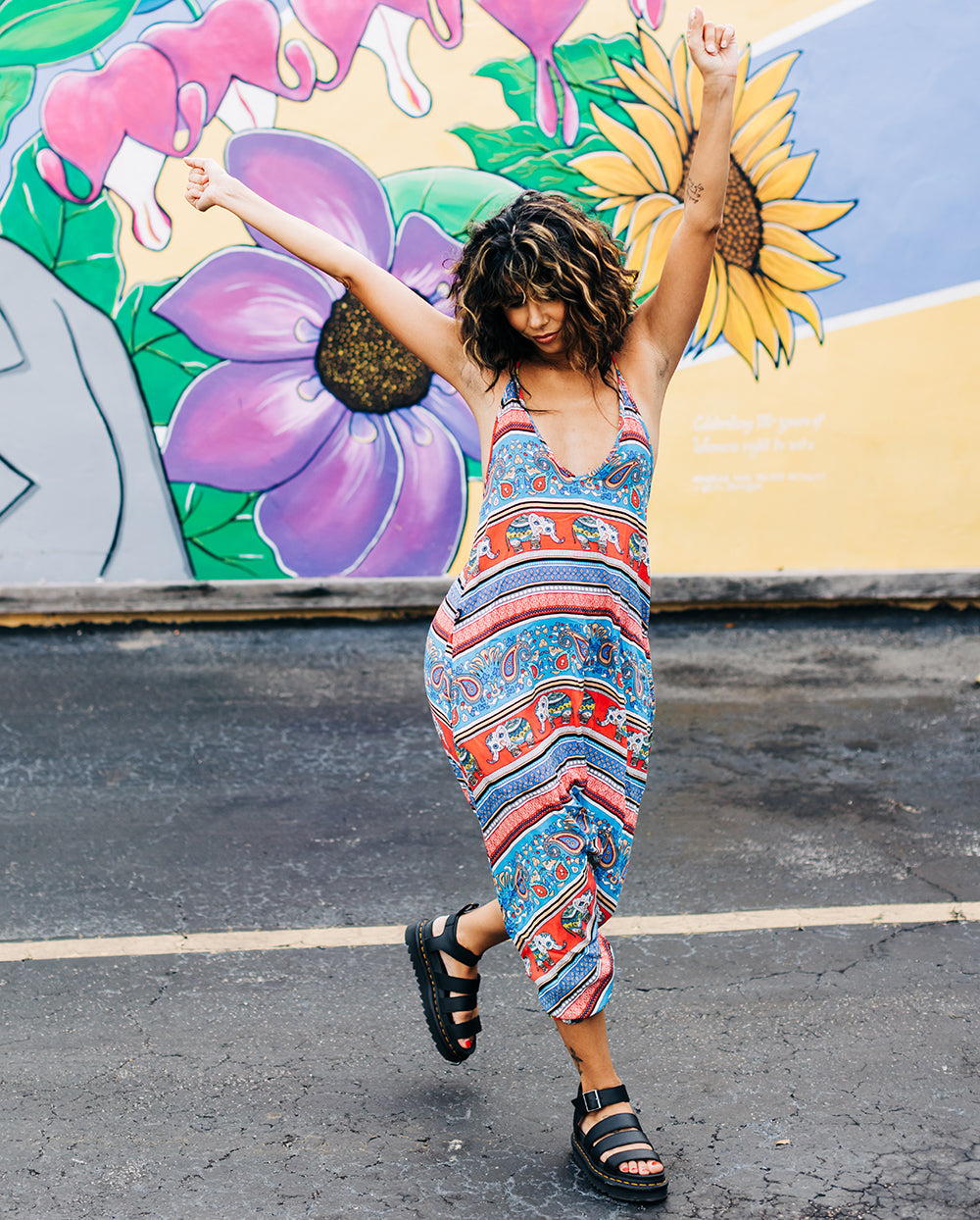 Urban mural background with woman in red elephant print jumpsuit #color_red elephant