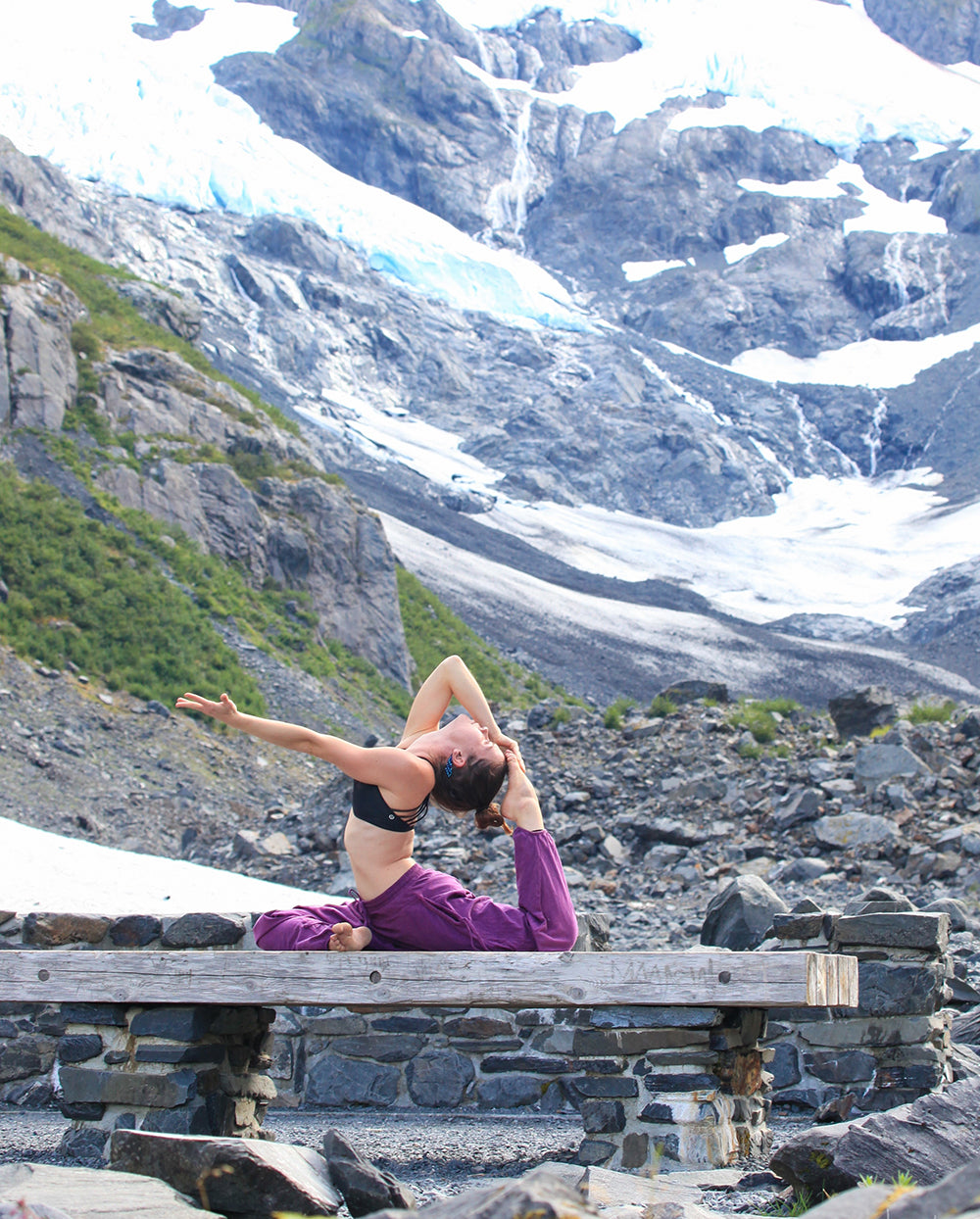 Person practicing yoga on a bench with a glacier in the background #color_purple