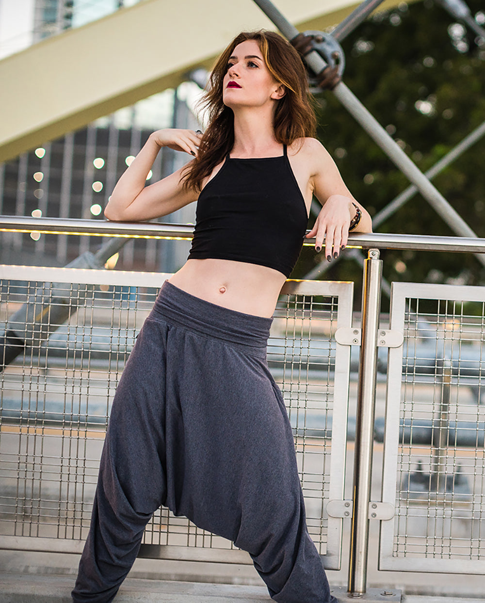 Woman wearing a black crop top and gray harem pants standing on a bridge. #color_grey