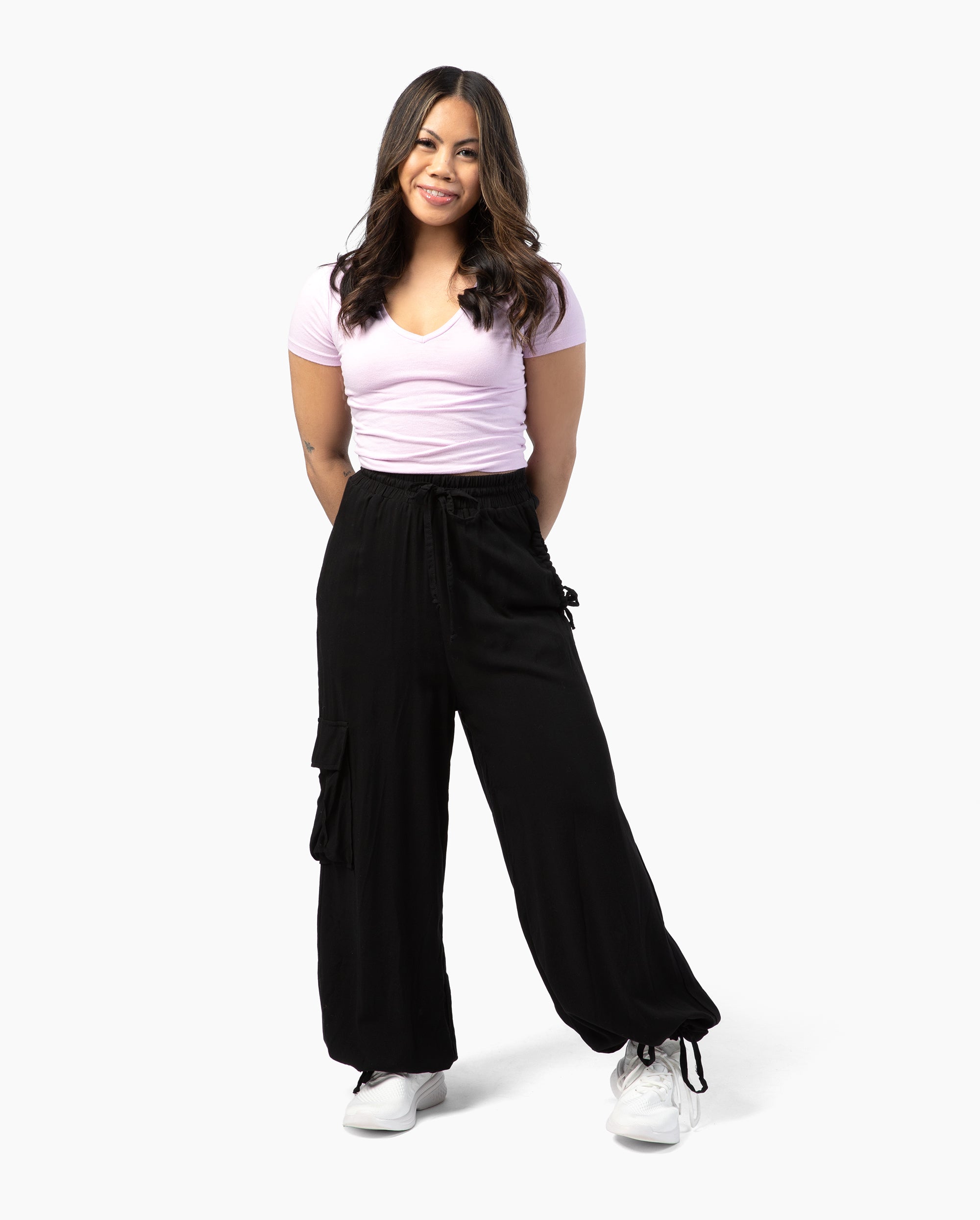 Woman wearing a pink t-shirt and black cargo pants on a white background #color_black