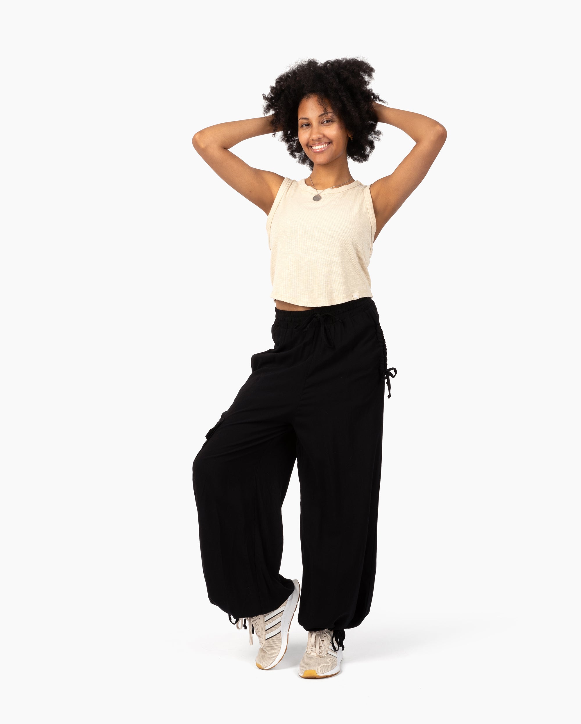 Woman wearing a beige sleeveless top and black high-waisted pants #color_black