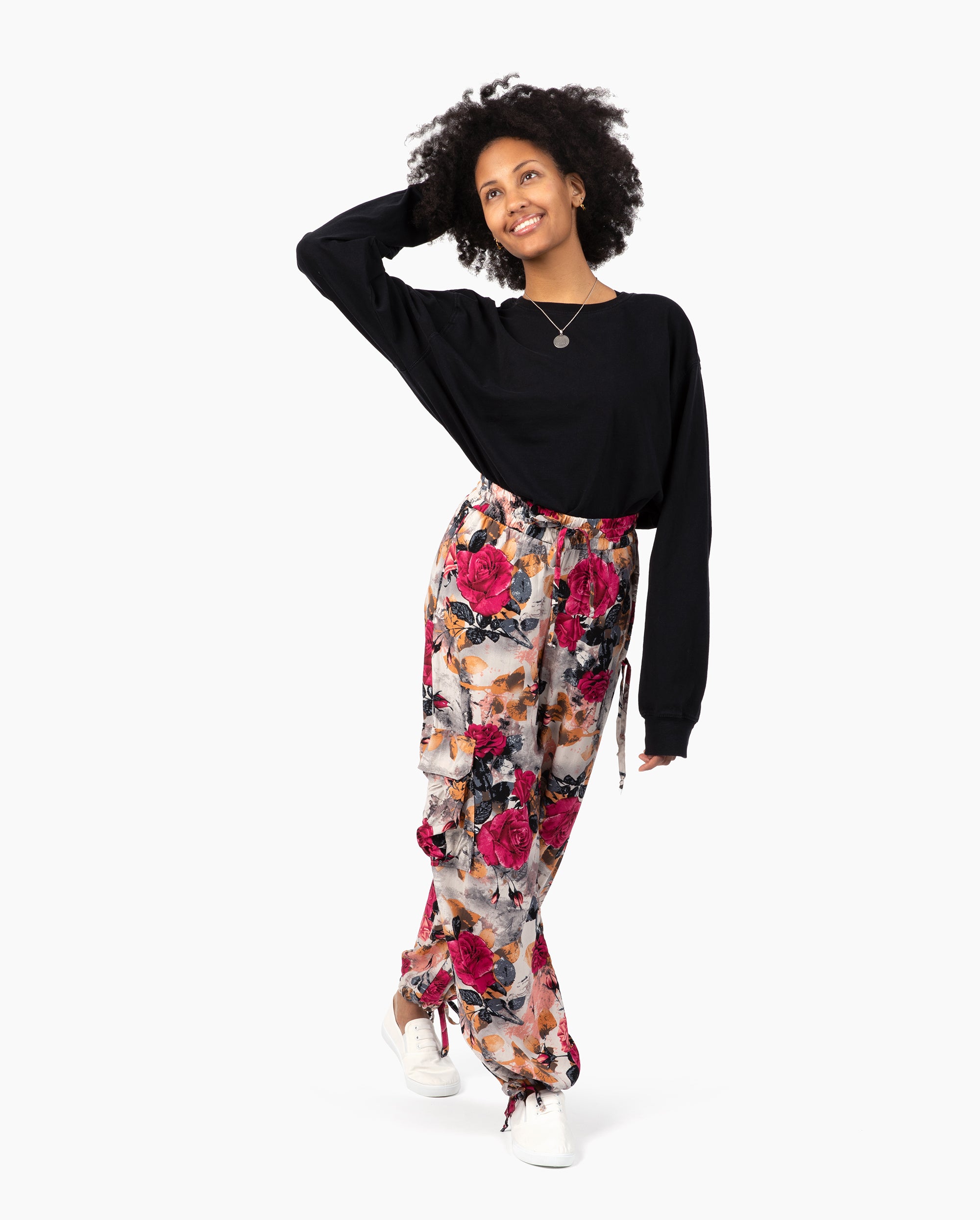 Woman wearing a black top and colorful floral pants on a white background #color_pink kira