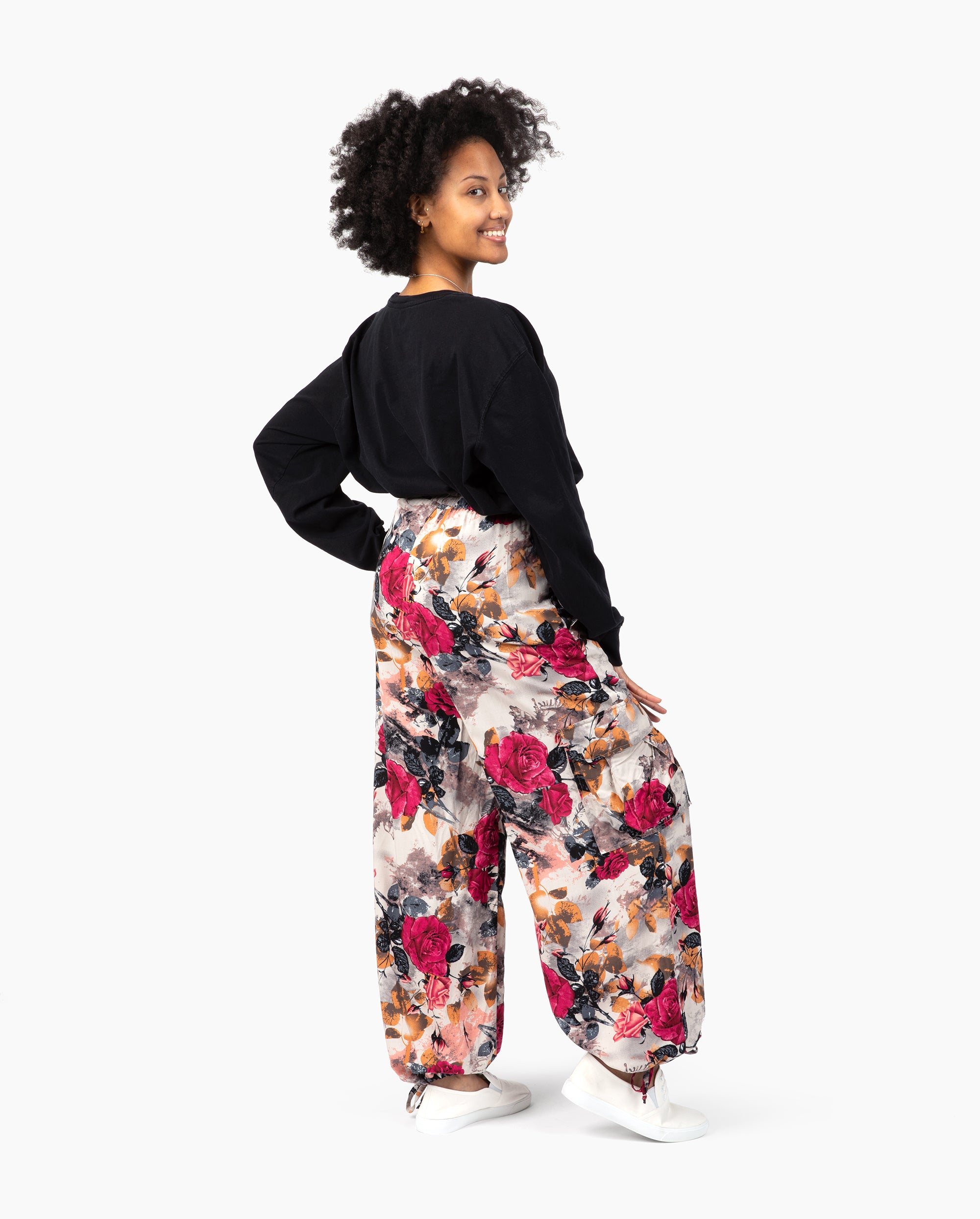 Woman wearing a black top and floral pants on a white background #color_pink kira