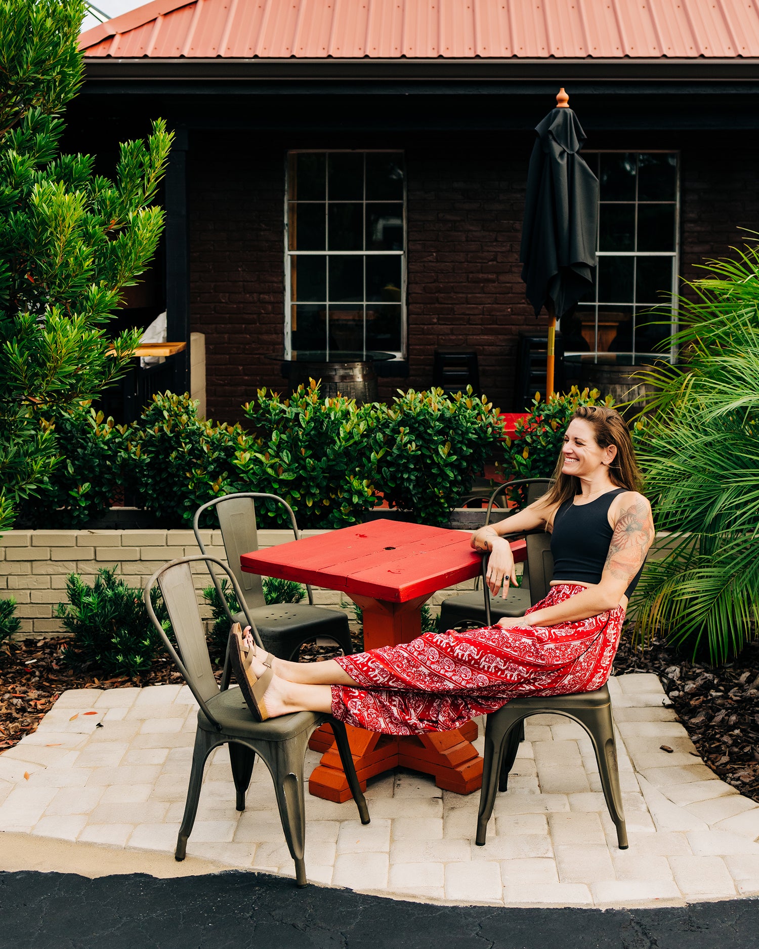 Woman relaxing on bench in red lotus elephant pants #color_red lotus