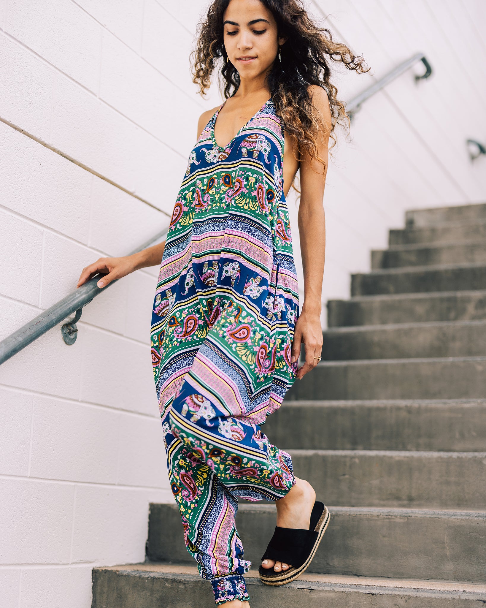 Model on stairs wearing pink elephant print Savannah Flair jumpsuit #color_pink elephant