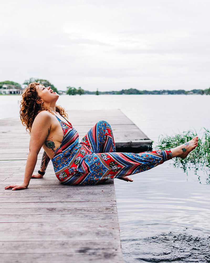 Woman lounging in Buddha Pants harem jumpsuit near lake #color_red elephant