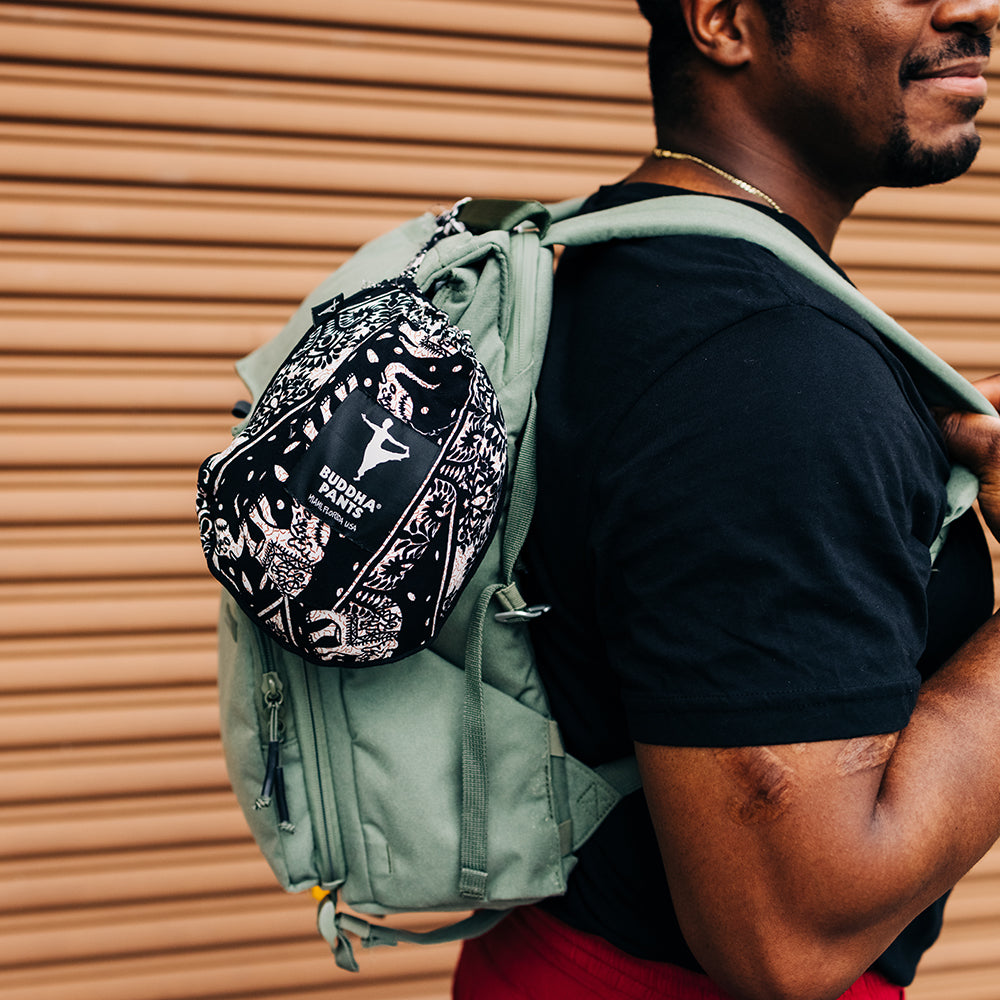 Male model with backpack wearing black lotus harem pants #color_black lotus