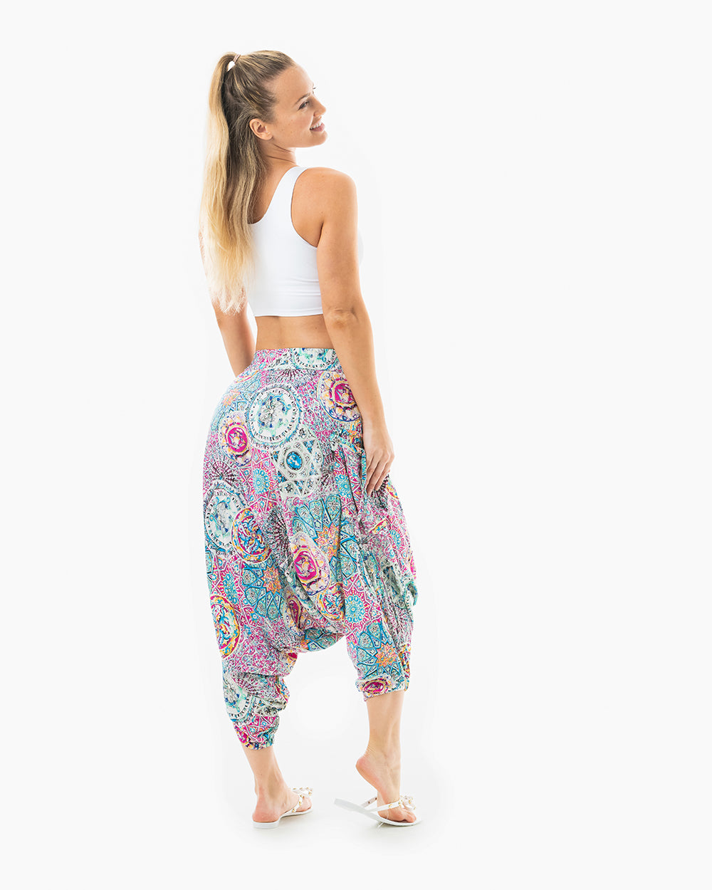 Blonde woman posing in purple galactic harem pants on white background #color_purple galactic