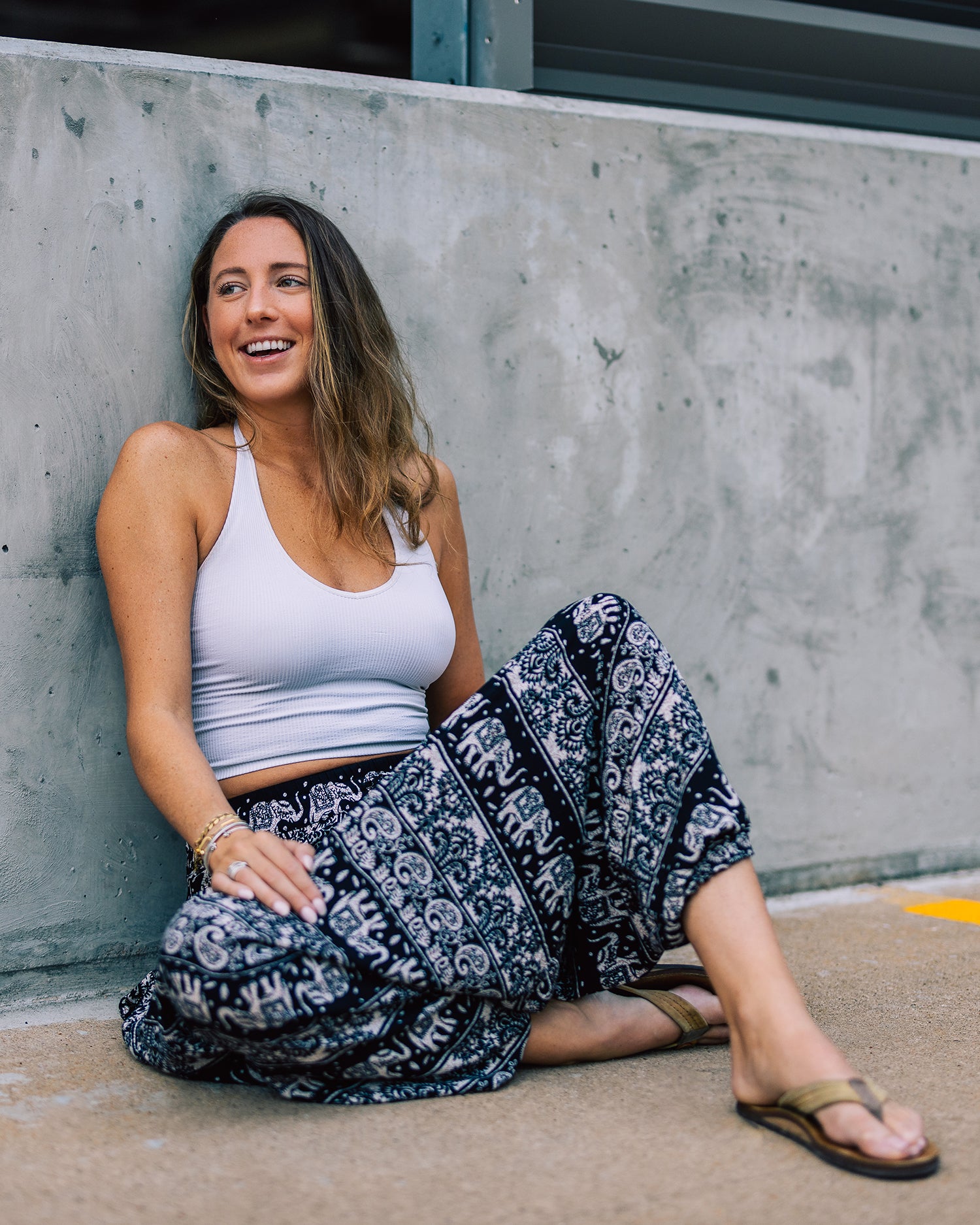 seated woman in black monk harem pants #color_black lotus