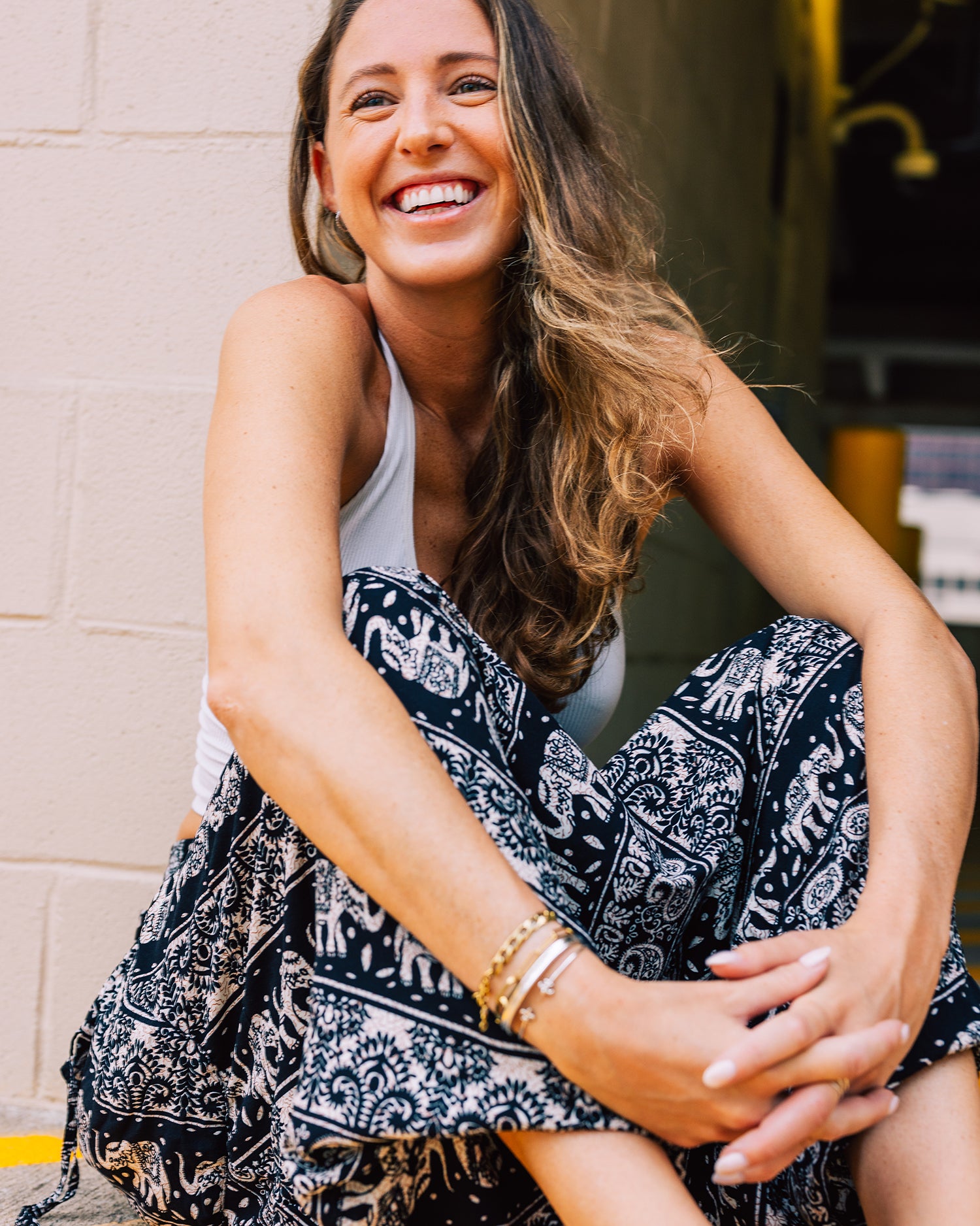 smiling model seated in black yoga pants #color_black lotus