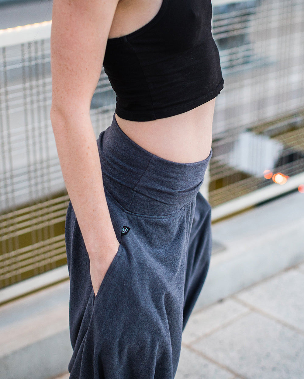 Person wearing dark gray pants and a black top outdoors. #color_grey